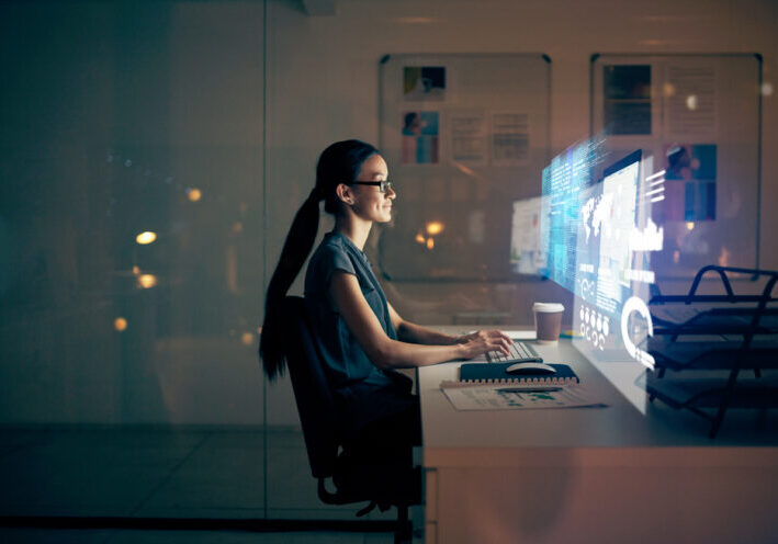 Shot of a young programmer using a computer at night in a modern office